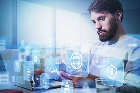 Businessman wearing white pullover is working on laptop with hologram of globe, coin, padlock, cloud...