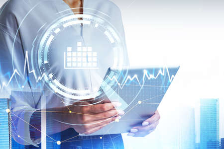 Businesswoman wearing white shirt is holding tablet. Digital interface with circle hologram and...