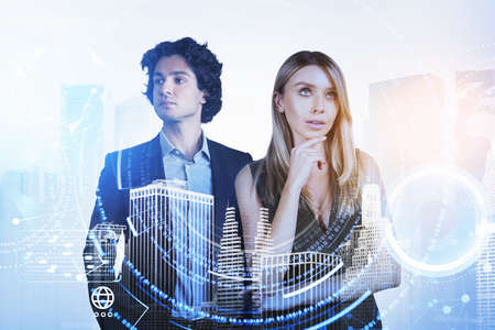 Businesswoman and businessman wearing formal suit are working together holding chin. Digital interface hologram in the foreground. New York city skyscraper in the background. Concept of teamworkの写真素材