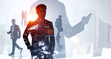 Silhouettes of group of business people work together discussing and talking about future of company. Singapore and New York city skyscrapers in the background. Concept of teamwork and cooperationの写真素材