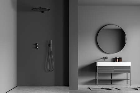Dark gray shower room interior with the shower area, a round mirror with the modern vanity and a concrete floor. A concept of stylish house design. 3d renderingの写真素材