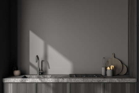 Close view on dark kitchen room interior with gray empty wall, sink, electric cooker, spoon and desk. Contemporary minimalist design. 3d renderingの写真素材