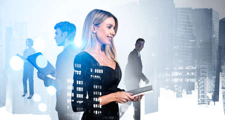 Smiling businesswoman wearing black dress is holding notebook. Group of business people work together taking notes for company. Singapore city skyscraper in background. Concept of teamworkの写真素材