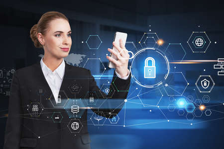 Attractive businesswoman holding smartphone and looking into the touch screen, blue glowing information protection icons. Padlock, cloud and digital interface. Concept of cyber security.の写真素材