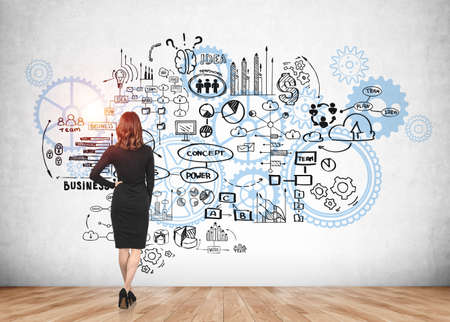 Businesswoman is standing near sketch with cogwheels, gear, light bulb, business, plan, teamwork, success on concrete wall and wooden floor. Concept of imagination and inspiration for creative ideasの写真素材