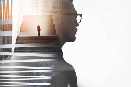 Side view of young businessman in glasses looking at blank wall with double exposure of stairs with another man. Career ladder concept.の写真素材