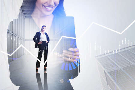 Two businesswomen working on project. CEO with hands on waist and smiling colleague checking data in smartphone. Financial charts with candlesticks, office and low angle skyscraper. Double exposureの写真素材