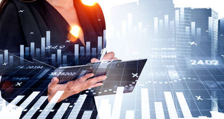 Businessman in formal suit is taking notes on clipboard. Singapore city skyscraper in background. Financial chart, bar diagram and graph. Concept of digital technologies and trading on stock marketの写真素材