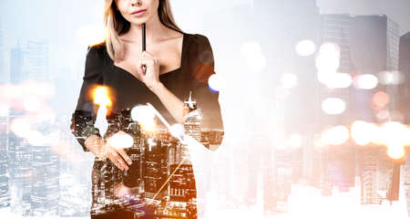 Businesswoman wearing black dress is standing and holding notebook touching her chin with a pen. Concept of imagination and inspiration for creative ideasの写真素材