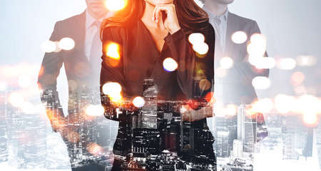 Businesswoman wearing black dress is holding her chin. Group of business people work together for company. Singapore city skyscraper in background. Concept of teamwork and cooperationの写真素材