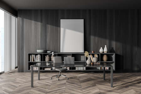 Empty canvas standing next to black wood wall in manager office interior with simple grey desk,...