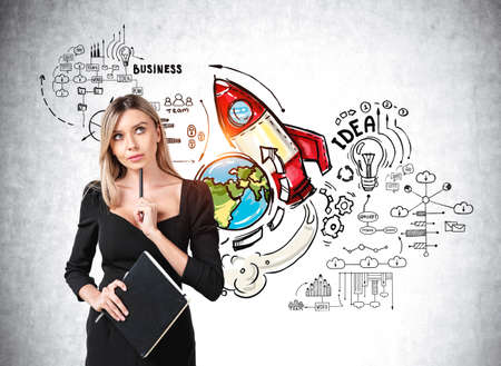 Young attractive businesswoman wearing formal dress is holding notebook. Sketch with rocket launch start up, globe, light bulb, cloud data storage, teamwork. Concept of international businessの写真素材
