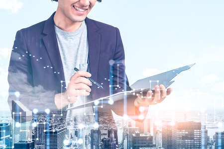 Office man in casual clothes, double exposure with skyscrapers roofs cityscape, rising chart with glowing stock market candlesticks. Concept of financial analysis and tradingの写真素材
