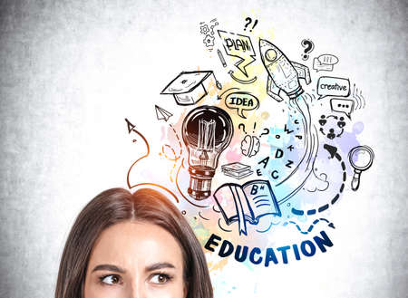 Office woman ponder, concentrated look, analysing colorful doodle drawing of university education, light bulb, e-learning and science icons. Concept of career developmentの写真素材