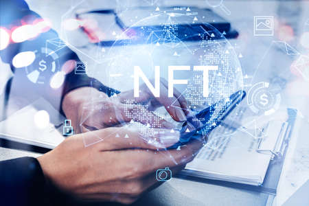 Woman hands with electronic device, touching screen with non-fungible token hologram, double exposure, nft with earth globe and office desk with documents. Concept of cryptocurrencyの写真素材