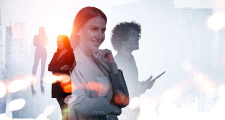 Office woman standing with arms crossed, pensive look. Silhouettes of diverse business people working together, blurred background of skyscrapers. Concept of communication with partnersの写真素材