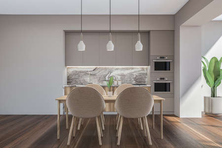 Bright kitchen room interior with empty beige wall, four chairs, double oven, dining table, cupboard...