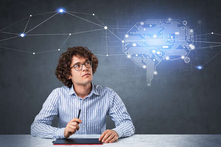 Businessman wearing formal shirt is sitting and using tablet at marble desk. Chalkboard with...