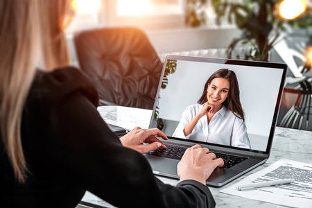 Two office women have online conversation, hands and laptop on desk with notebooks in manager room,...