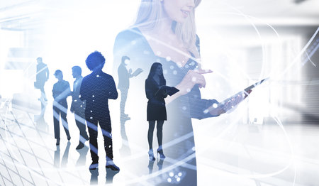 Office woman finger point at device, silhouettes of diverse business people working together, office room and worldwide connection. Concept of teamwork and communicationの写真素材