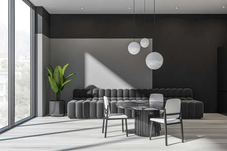 Gray living space with stylish couch, spherical pendant lights and round dining table with three...