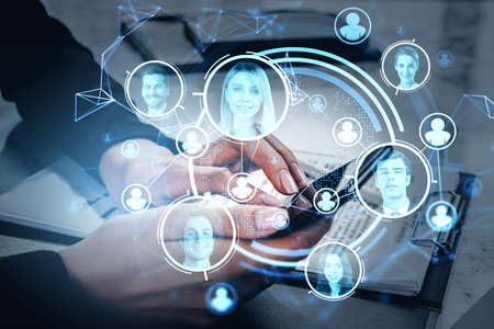 Office woman using smartphone and business contract in office room. Blue hud glowing hologram with diverse people portraits, double exposure. Concept of technology and human resourcesの写真素材