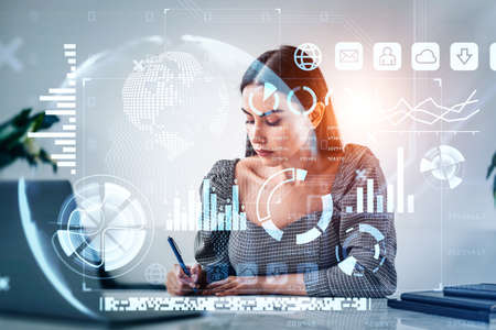 Office woman working in office room, double exposure, financial data and business bar chart. Graph lines, pie chart and sphere. Concept of worldwide businessの写真素材