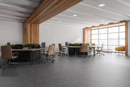 Corner view on bright office room interior with panoramic window, twelve laptops, comfortable...