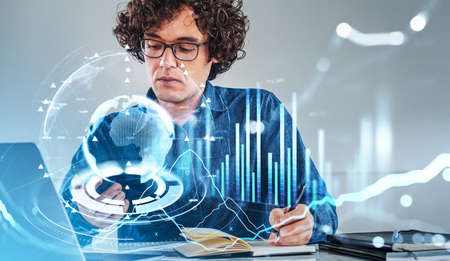 Office man student working with smartphone and writing in notebook, hud with stock market dynamics...