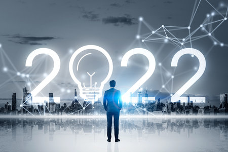 Businessman wearing formal suit is watching at New York city skyscraper financial downtown center with reflection. 2022 new year sign with light bulb, line connection. Dark gray skyline. 3d renderingの写真素材