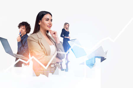 Smiling young attractive businesswoman wearing formal suit is touching her chin. Financial rising graph in the background. Concept of teamwork, cooperation and coworking in trading on stock marketの写真素材