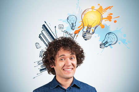 Office man smiling and inspired look, bright lightbulb with financial plan doodle. Business sketch graphs on blue wall. Concept of startup and new ideaの写真素材
