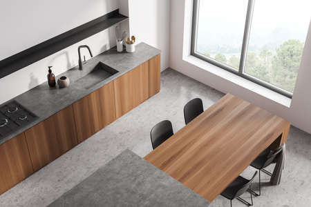 Top view on bright kitchen room interior with panoramic window, dining table with chairs, sink, electric cooker, cupboard and concrete floor. Concept of minimalist design. 3d renderingの写真素材