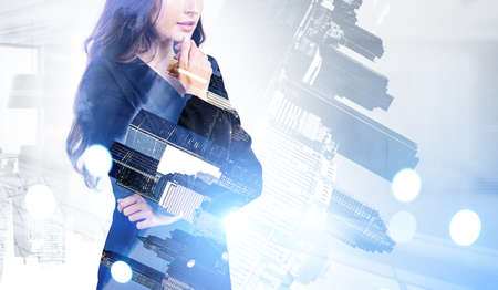 Woman manager in business suit with thoughtful look, mba student. Double exposure with office buildings in New York at night. Concept of personal development and careerの写真素材