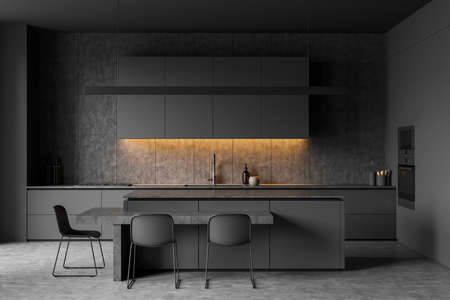 Dark kitchen room interior with cupboard, electric cooker, double oven, table with three chairs, gray wall, sink, oil and concrete floor. Concept of minimalist design. 3d renderingの写真素材