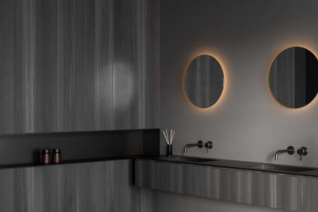 Gray washing room interior with two sinks and two separate mirrors with backlight on wall, side view, bathing accessories on wooden deck, gels bottles and reed diffuser. 3D renderingの写真素材