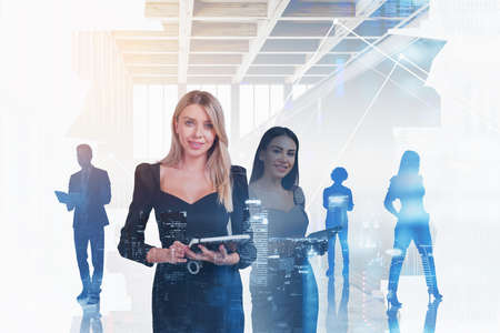 Two businesswoman smiling, working together. People silhouette talking and thinking. Double exposure of skyscrapers at night and office room. Concept of network and technologyの写真素材