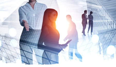 Silhouettes of diverse business people working together, woman handshake and partners talking, double exposure of city skyscrapers, toned image. Concept of communication and recruitmentの写真素材