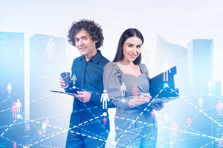 Businessman and businesswoman smiling, social media icons hologram, panoramic city view. Concept of...
