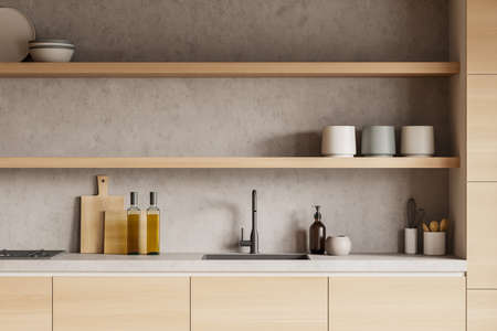 Wooden kitchen interior with countertop and sink, deck with kitchenware, front view. Rack with...