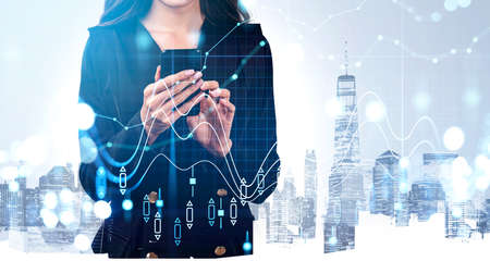 Businesswoman wearing formal suit is typing message on smartphone. New York city skyscrapers in the...