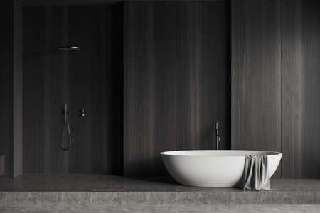 Dark bathroom interior with bathtub and shower on podium, gray concrete floor, front view. Hotel washing room with copy space empty black wooden wall, 3D renderingの写真素材