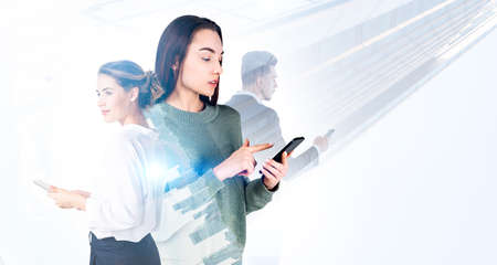 Young attractive businesswoman works together with colleagues using smartphone. New York city...