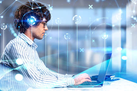 Handsome curly businessman wearing formal shirt is working on laptop. Blurred background. Concept of...