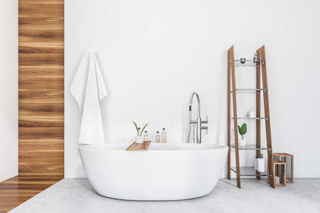 White bathroom interior with tub on gray concrete floor, shelf with bathing accessories and decoration. Washing room in hotel with gels and towels, 3D renderingの写真素材
