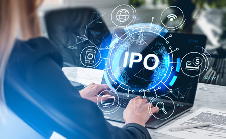 Businesswoman wearing formal suit is working on laptop trading on stock market. Office workplace with desk in the background. Digital interface with virtual globe. Concept of successful IPOの写真素材
