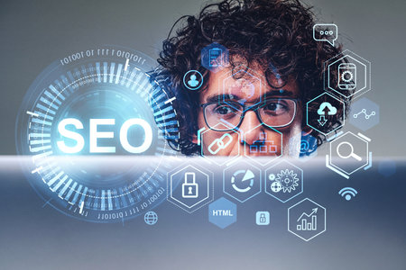 Curly businessman is working on laptop with digital interface with seo, search engine optimization. Concept of modern technology of website analysis, keywording, content, ranking and social mediaの写真素材