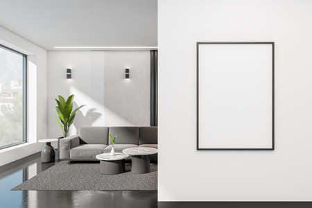 Modern living room interior with sofa and coffee table, dark concrete floor. Panoramic window on countryside. Mockup poster on front entrance. 3D renderingの写真素材