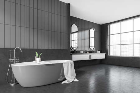 Corner view on dark bathroom interior with bathtub, panoramic window with city view, stool with shampoo and towels, mirrors, sinks, gray walls, concrete floor. 3d renderingの写真素材
