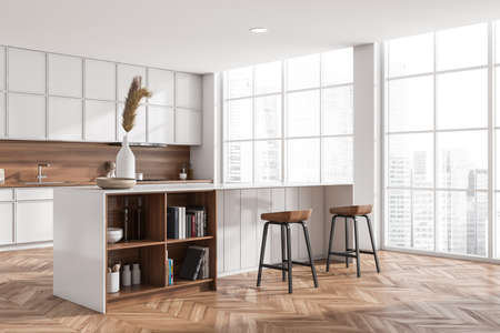Light kitchen interior with bar chairs and island, side view, hardwood floor. Art books and dishes...